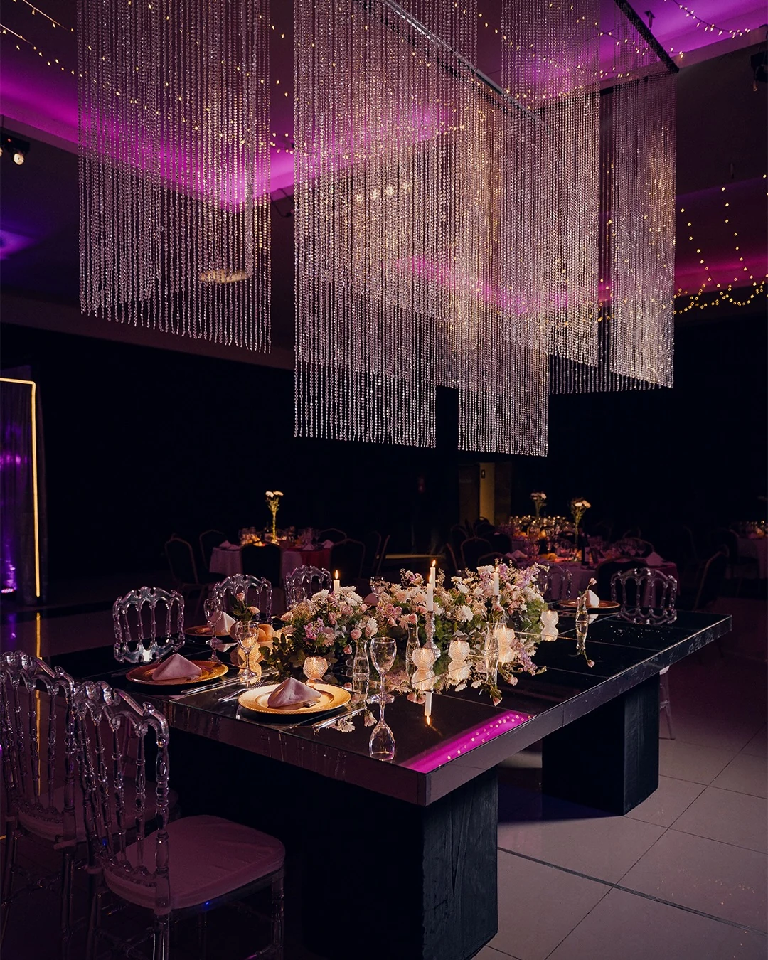 Mesa de La Florentina con flores, cristales y reflejos de iluminación violeta